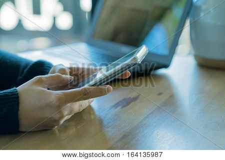 Businesswoman working with modern devices laptop computer and mobile phone in coffee shopwoman's hands using smart phone in interior woman at her workplace using technology .