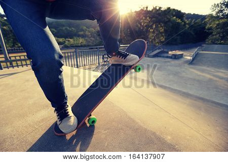 young skateboarder legs riding skateboard at skatepark