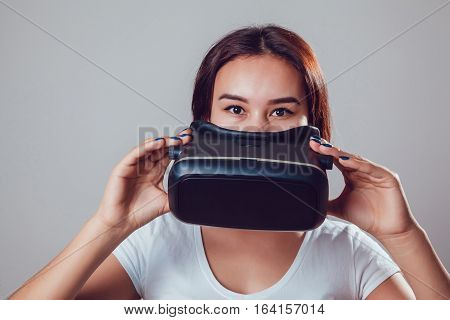 Attractive woman wearing virtual reality goggles. VR headset. Virtual reality concept on grey background.