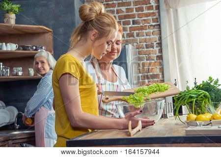 Happy family cooking together vegetable salad in kitchen