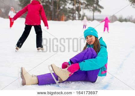 Young Attractive Skater Girl Sitting On The Ice