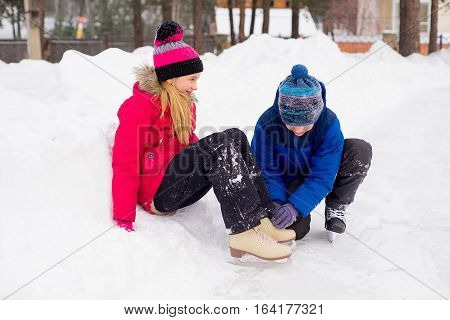 Young Boy Helps To The Girl Ties Bootlaces Up Skates