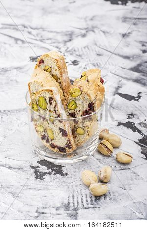 Crispy traditional delicious Italian biscotti cookies or kantuchchi with pistachios and dried cranberries in a glass on a marble background. selective focus