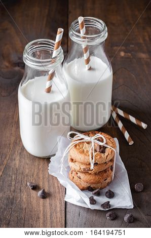 Milk bottles and chocolate chips cookies. Toned image. Selective focus on cookies.