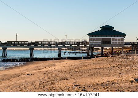 Morning light on fishing pier with sandy beach at Buckroe Beach in Hampton, Virginia.
