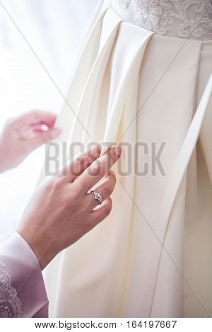 girl corrects a wedding dress before the wedding hand