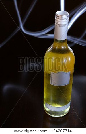 Generic wine bottle lit only by a torch. Light patterns in the background.