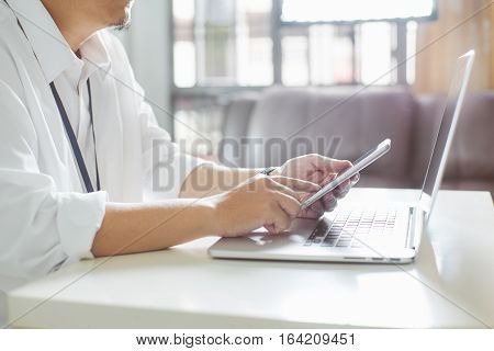 businessman hand using smart phone with laptopclose up Seleted focus.