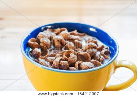 close-up a cup of fresh milk mixed with cereal and red spoon prepare for breakfast on wooden table