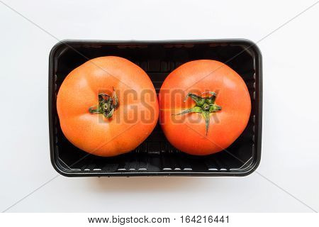 Two tomatoes in the unpack black plastic box from supermarket healthy foods
