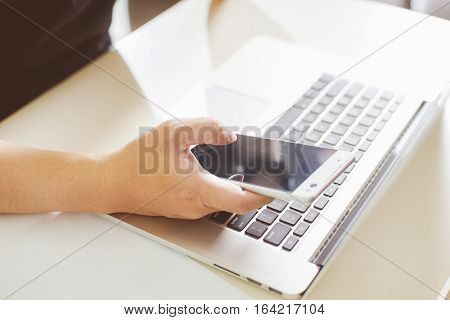 Young man hand using smart phone and laptopclose up Seleted focus.
