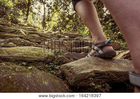 Closeup of female legs wearing sandals ascending forest staircase. Walking in jungle of Lake Phewa, Pokhara in Nepal.