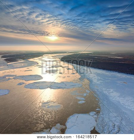 Aerial view great river with spring debacle during sundown. Floating of ice.