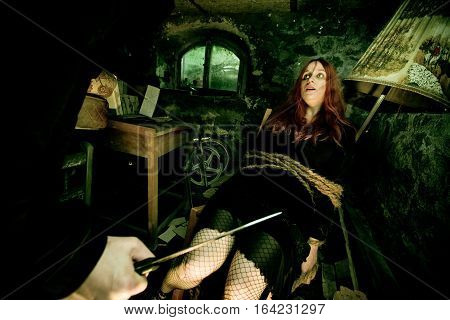 young woman tied to a chair in a dirty cellar