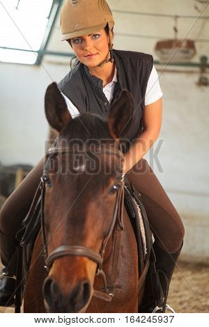 a young woman riding her horse in an indoor riding arena