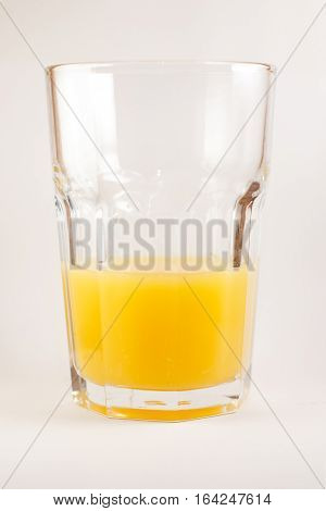 Three-quarters of a highball glass of fresh orange  juice on white background