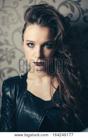 Punk rock style or halloween make-up. Fashion woman model face with bright glamour makeup. Perfect skin, black gloss eyeshadows on eyes and dark brown glossy lips visage. Portrait close-up. Vintage colours.