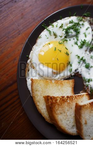 Delicious fried eggs for breakfast on a wooden table with grilled bread