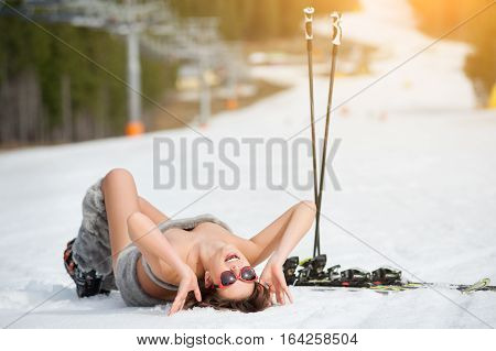Sexy Smiling Female Skier Is Lying On Snowy Slope Under Ski Lift