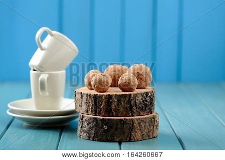 Homemade yummy chocolate balls on wood slabs with coffee cups on turquoise background with copyspace