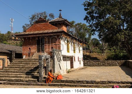 Bandipur Nepal - NOVEMBER 24 2016: Nepali aged pilgrim in orange robe in the temple of Bandipur in Nepal November 24 2016.