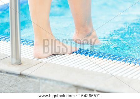 Young woman testing the water, closeup on feet.