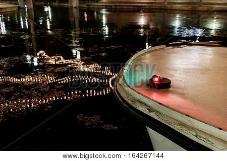 Bow of a boat in the water with Christmas light relfection.