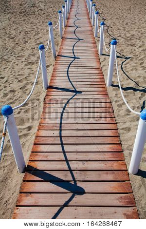 Wooden walkway over the sand dunes to the beach. Beach pathway in Lido di Ostia ( Lido di Roma) private beach Salvataggio Italy.