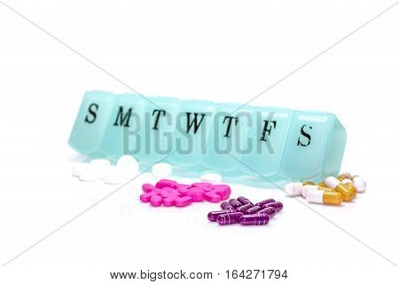 Pill box with assorted pills isolated on white with narrow depth of field.