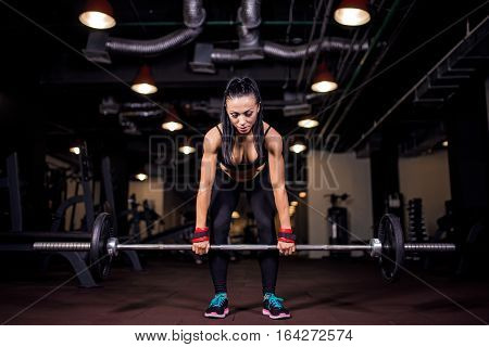 Muscular young fitness woman doing heavy deadlift exercise in gym