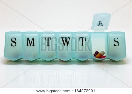 Pill box with Friday's pills visible on white background.