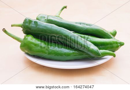 Green vegetables. Organic long green peppers on white plate selective focus horizontal