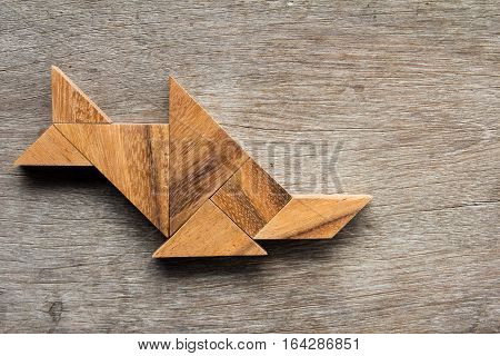 Wooden tangram as fish shape (sawfish) on old wood background