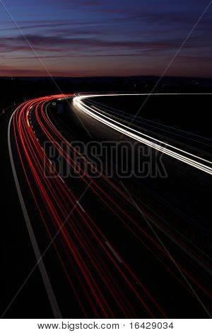 Auta ve spěchu pohybující se rychle na dálnici (speedway) za soumraku