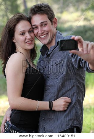 Bela jovem casal caucasiano, se divertindo ao tirar fotos de autoportrait de si ao ar livre