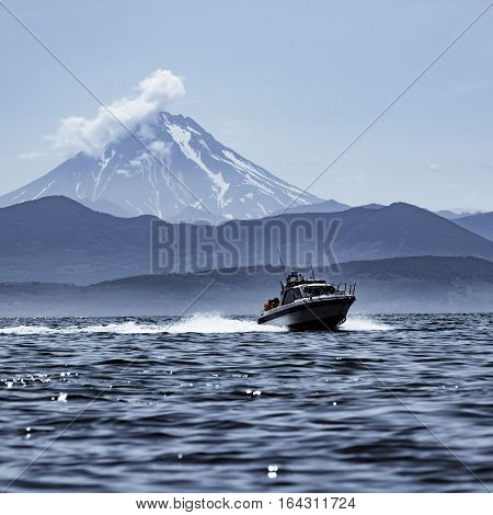 The Sunday at noon. Viluchinsky volcano, the sky, the clouds, the bay, the boat.