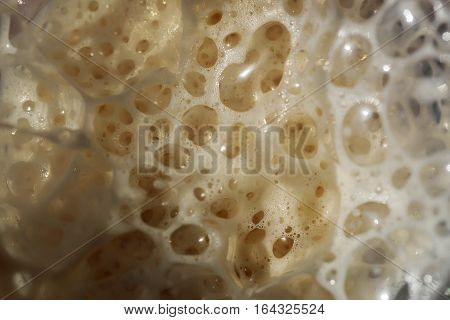 Beige carbonated beverage foam with bubbles texture as abstract background