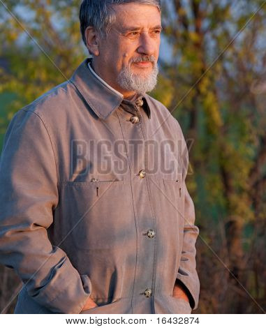 Muotokuva komea vanhempi mies seisoo ulkona lämmin iltavalaistuksessa