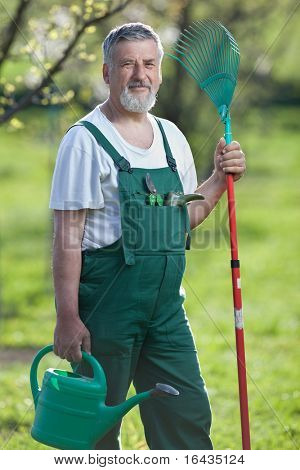Ritratto di un giardiniere anziano bello in un giardino