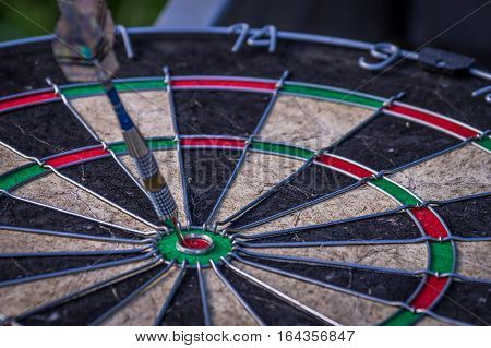 Dart arrow hitting in the target center of dartboard illustrates the achievement of goals