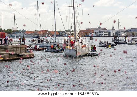 Copenhagen, Denmark, July 15, 2016 - People greeting popular danish salingboat after circumnavigation with shooting flags in the air.