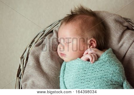 Newborn baby with a Mohawk hairstyle is sleeping in the basket