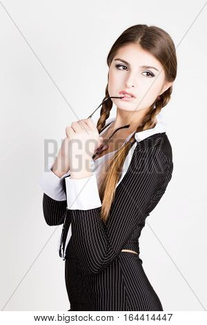 sexy secretary, portrait of beautiful brunette business lady wearing in pinstripe suit biting the handle of glasses.