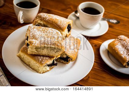 Baked sweet buns with poppy and coffee on wood table