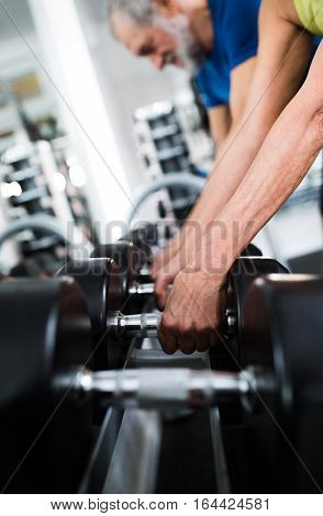 Close up of hands of senior couple in gym that is going to work out with weights