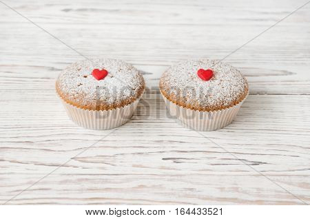 Two muffins decorated with red hearts on white wooden background. Love. Valentine's Day concept. Copy-space composition