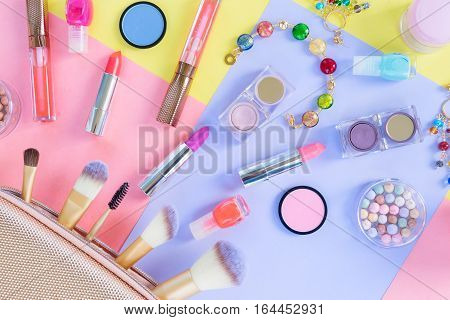 Colorful make up products with golden pursue close up pop art flat lay scene