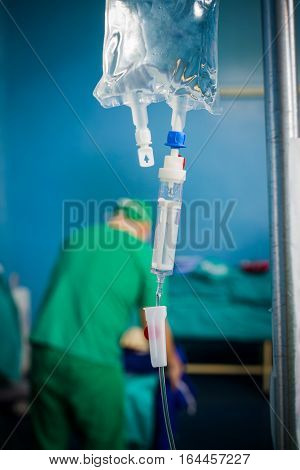 Focus on the perfusion bag with nutritions and plysiologycal saline doctor working in the background.