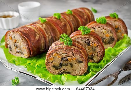 Oven baked meatloaf with bacon on a concrete grey background. Meatloaf stuffed with mushrooms potatoes carrots and onions