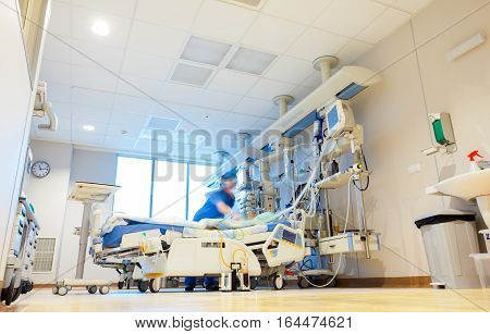 A hospital reanimation room with modern medical equipment and blurred patient and nurse or doctor figures.